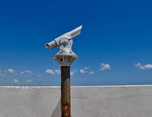 Close-up of coin-operated binoculars against blue sky