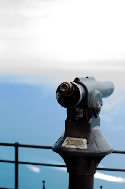 Photo close-up of coin-operated binoculars against sky