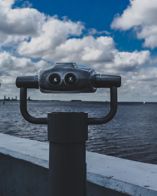 Photo close-up of coin-operated binoculars by sea against sky