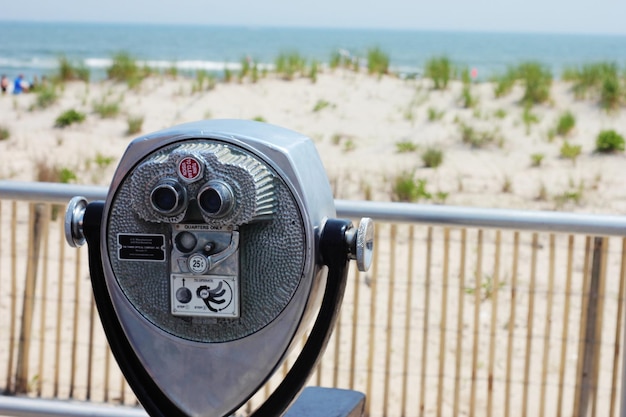 close-up of coin-operated binoculars by sea against sky