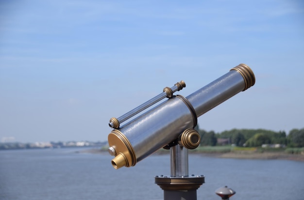 Close-up of coin-operated binoculars by sea against sky