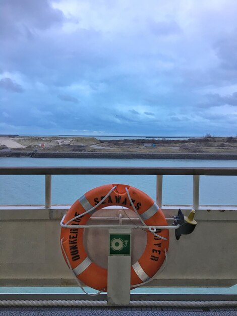 Close-up of coin-operated binoculars on sea against sky