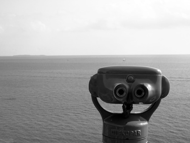 Foto close-up di binocoli a monete sul mare contro il cielo