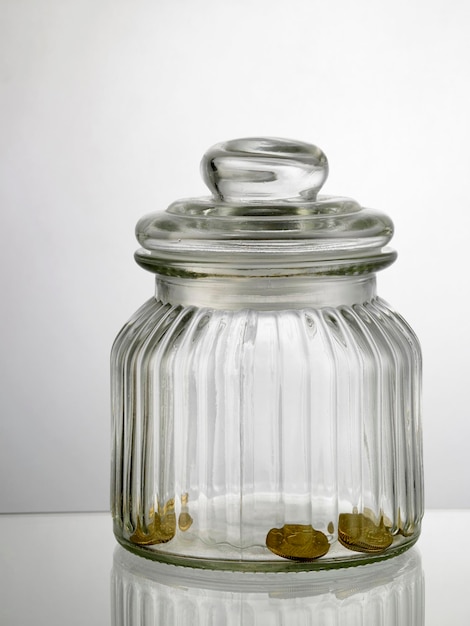 Close-up of coins in jar on table against white background