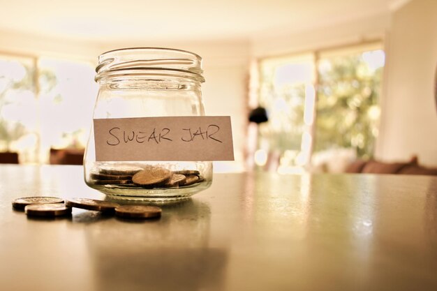 close-up of coins in jar with label on wooden table
