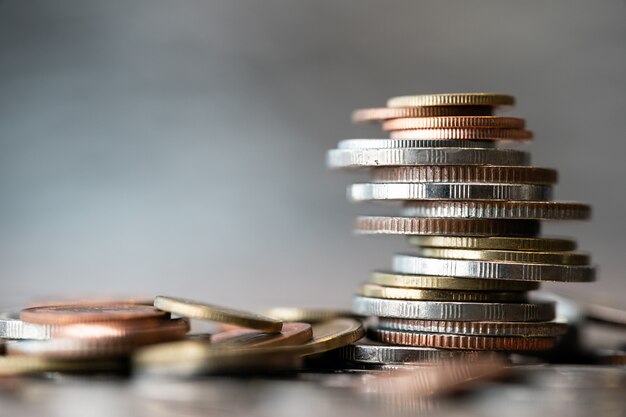 Close up of coins stacked with other in different positions on blurred background.