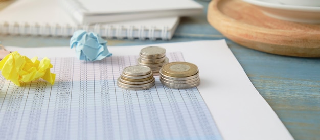 Close-Up Of Coins With Data By Computer On Office Desk