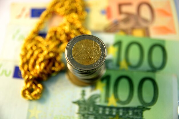 Close-up of coins with paper currency and gold chain necklace on table