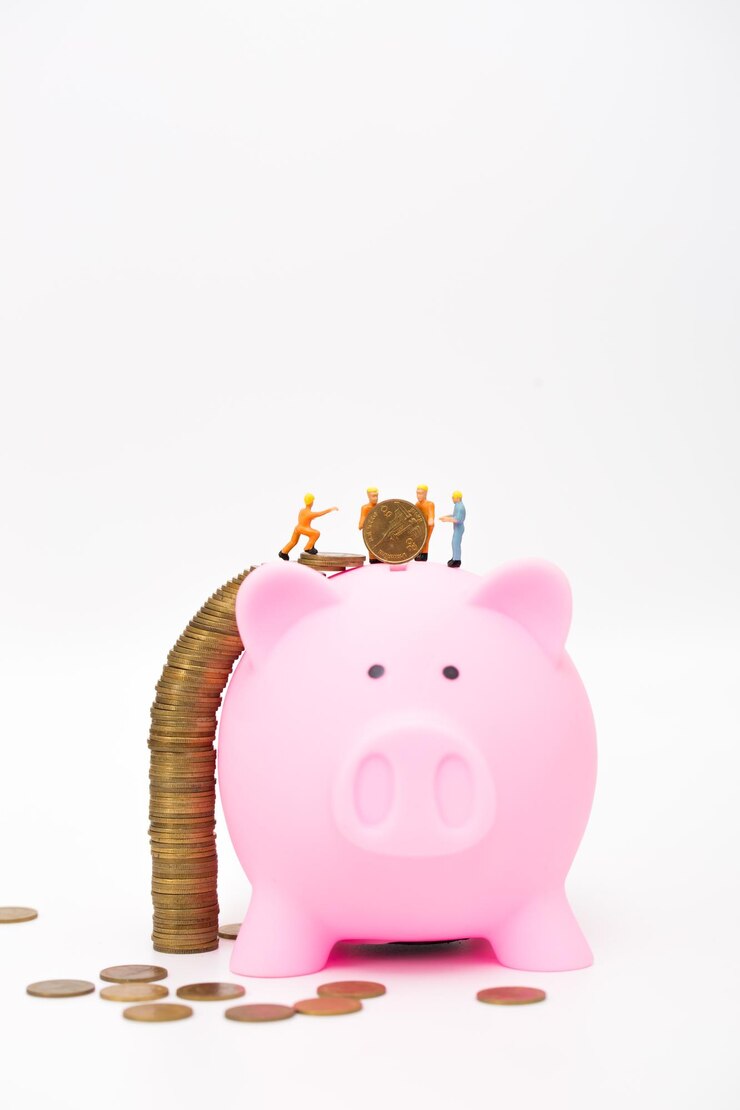 Photo close-up of coins with piggybank and figurines against white background