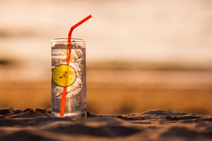 Photo close-up of cold drink on sand at beach during sunset