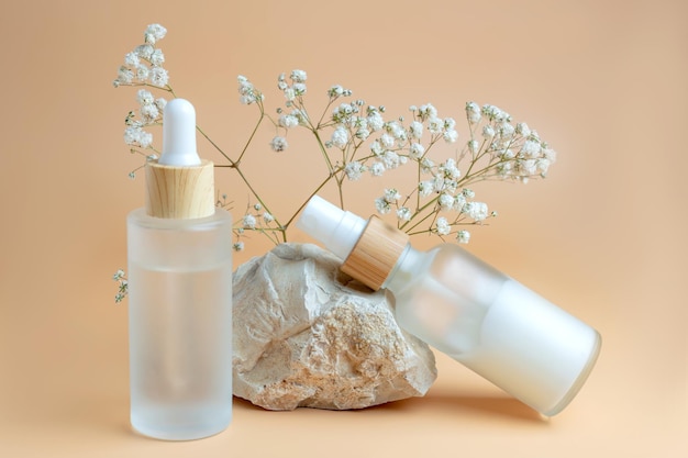 Close up of collagen cream in glass jar serum in frosted glass\
bottle and dry flowers on beige background set for skin and body\
care beauty products