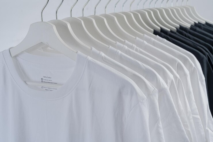 木製ハンガーに掛かっている黒と白のカラー t シャツのコレクションを閉じます