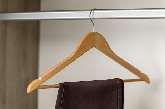 close up collection hangers with clothes on rack in wardrobe