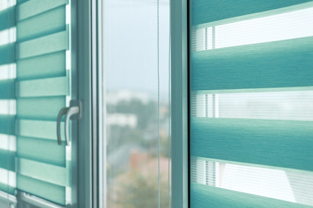 Close up of colored fabric roller blinds on window. Roll curtains.