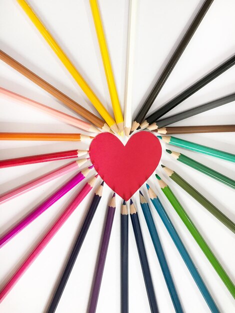 Foto close-up di matite colorate e carta a forma di cuore sul tavolo