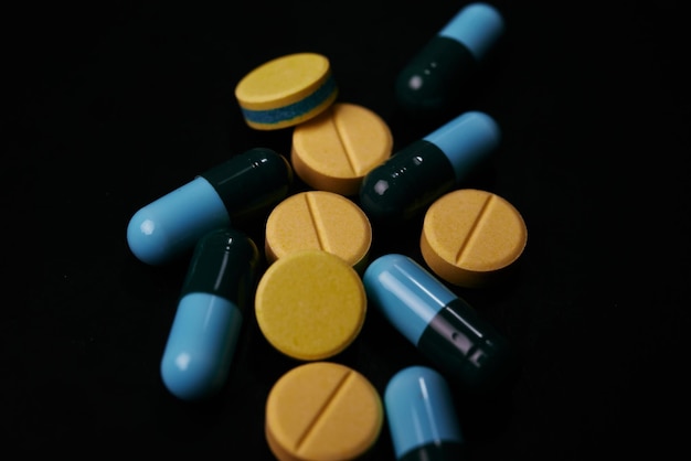 Photo close-up of colored pill and drugs over black background