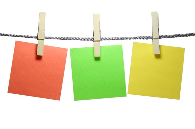 Photo close-up of colorful adhesive notes on rope against white background