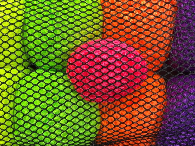 Photo close-up of colorful bath sponges seen through netting