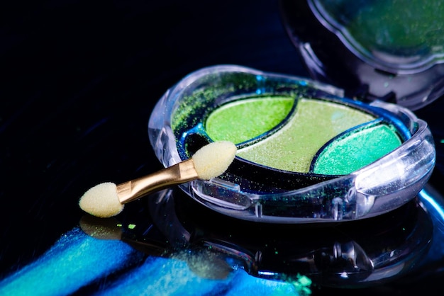 Крупный план красочной палитры теней для век и цветной макияж кисти с зелеными мерцающими тенями
