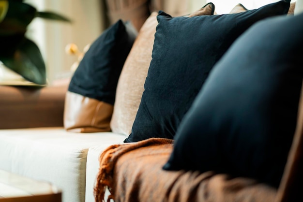 Крупным планом красочные мягкие подушки раскладывают на диване-кушетке с размытым видом на сад с прозрачным занавесом в гостиной, концепция дизайна интерьера дома