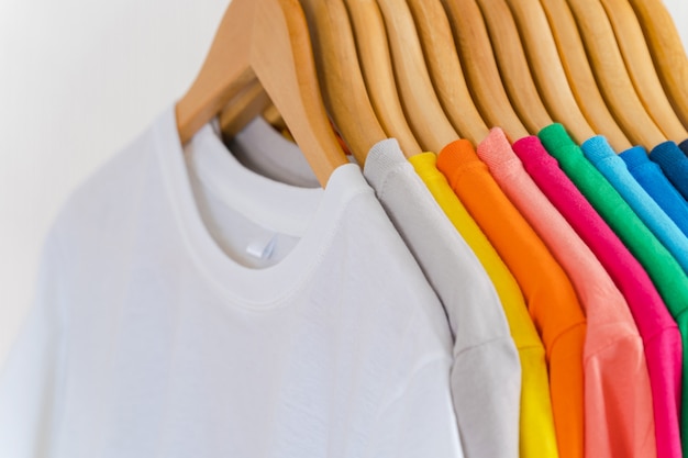 Photo close up of colorful t-shirts on hangers, apparel background