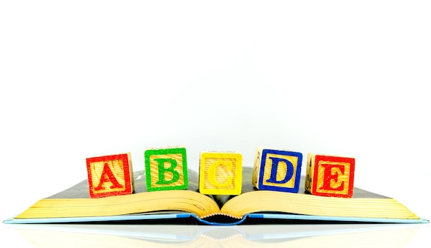 Close-up of colorful toy blocks with book over white background