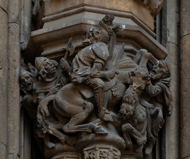 A close up of a column with a man on a horse and a horse on it.