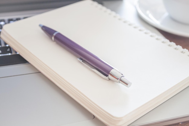 Close-up of computer keyboard with book and pen on table