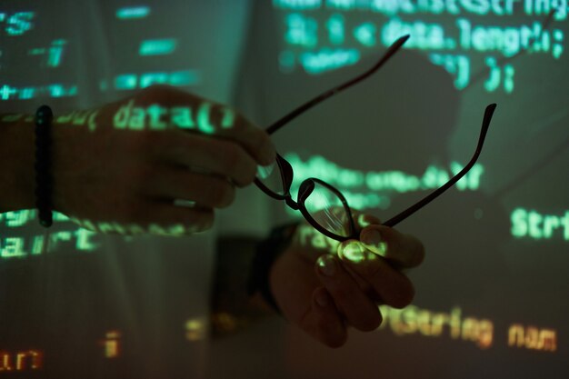 Close-up of computer programmer holding eyeglasses he protecting his eyesight while working with computers