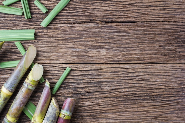 Foto chiuda sulla canna da zucchero di concetto su fondo di legno.