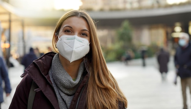 Photo close up of confident woman wearing medical mask in city street as prevention against virus