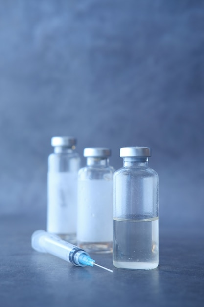 Photo close up of coronavirus vaccine and syringe on black wall