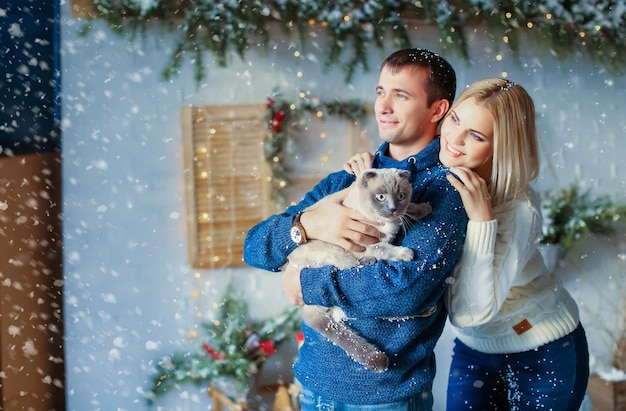 Close up of a couple on christmas eve with a pet cat in his arms