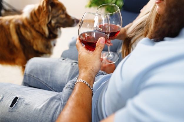 Close up of couple drinking wine on sofa with their border collie dog near