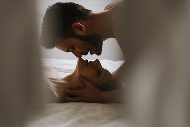 close-up of couple embracing while lying on bed at home