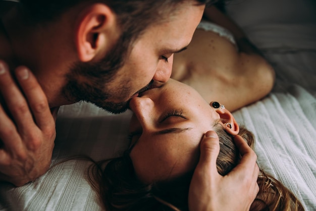 Close-up of couple embracing while lying on bed at home