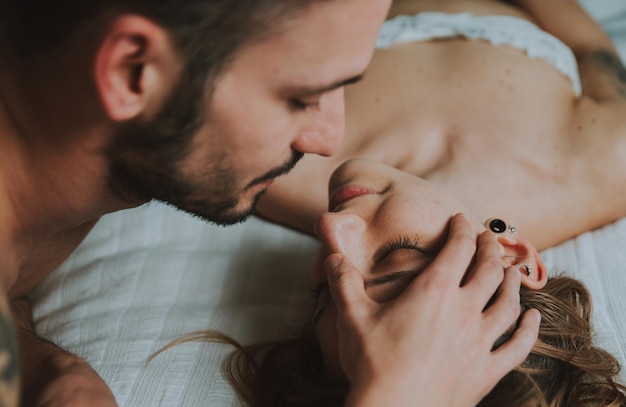Close-up of couple embracing while lying on bed at home