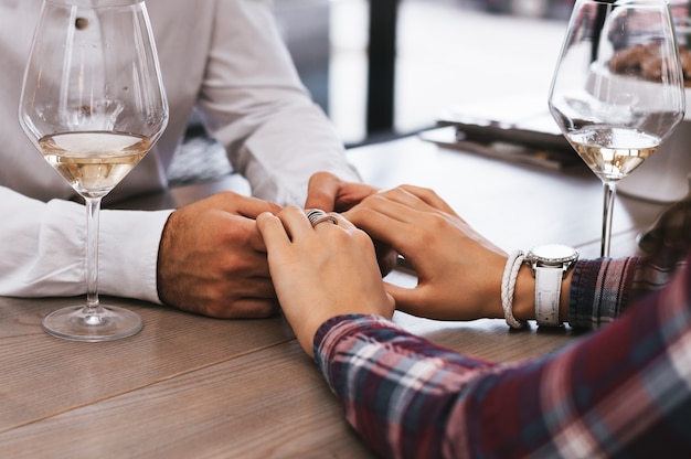  Close-up of couple holding hands while sitting together in cafe