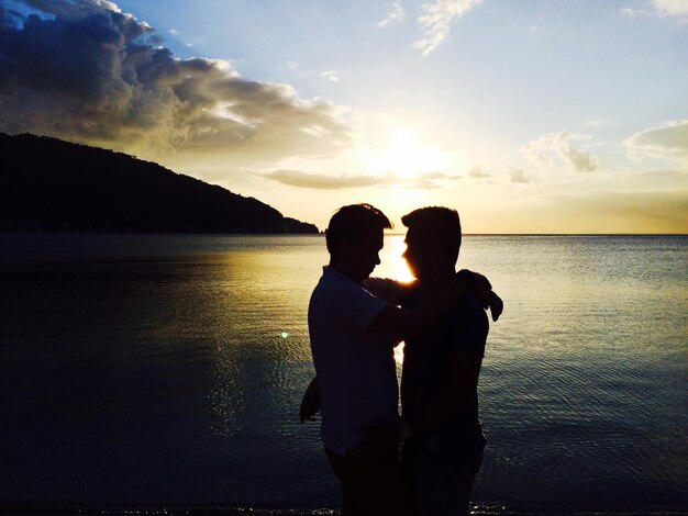 Photo close-up of couple standing against sea during sunset