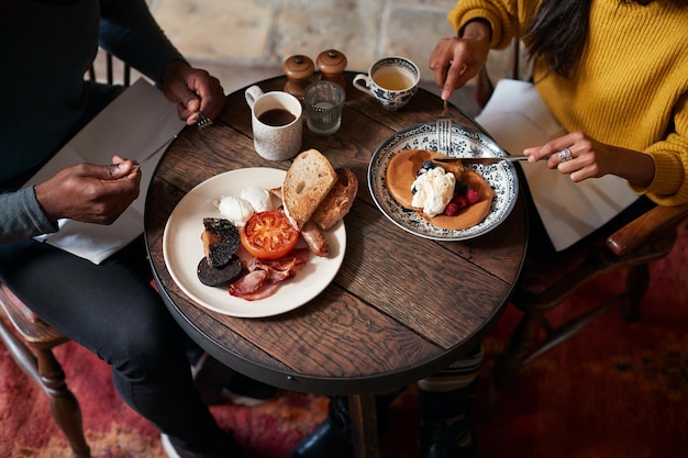 朝食を食べる伝統的な英語のパブのテーブルでカップルのクローズアップ