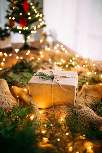 Close up on craft gift box on the wooden table with garland and fir branches