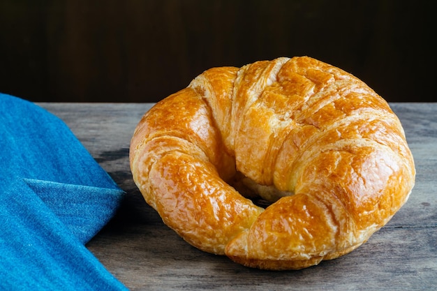 Foto close-up di un croissant con un tessuto blu sul tavolo