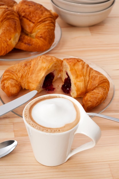テーブルの上で提供されるカプチーノとクローズアップのクロワッサン
