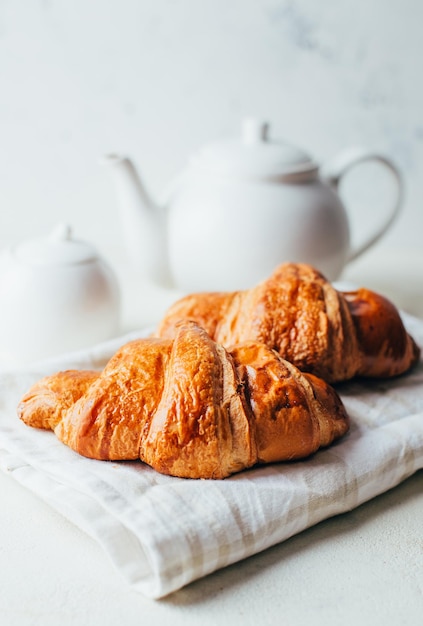 Close-up on croissants on the background of a white teapot on a white background