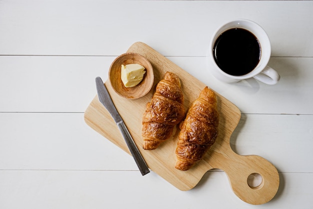 Close up of croissants served with butter and coffee on table in restaurant for breakfast