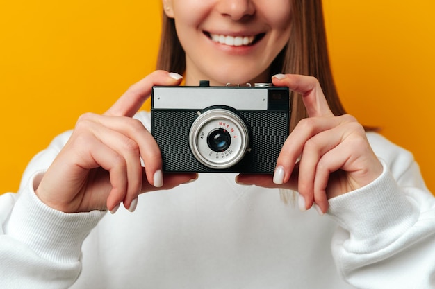 ビンテージ写真カメラを保持している広い笑顔の女性のクロップ ショットを閉じる