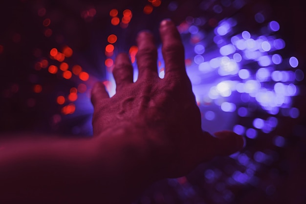 Close-up of cropped hand against defocused lights at night