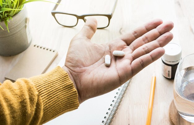 Photo close-up of cropped hand holding pills at table