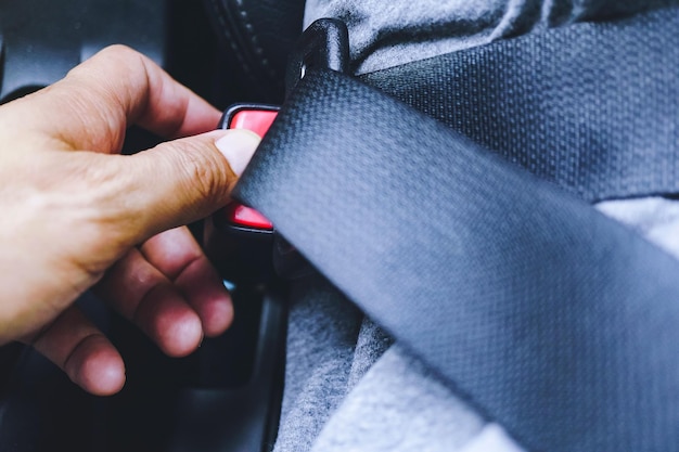 Foto close-up di una mano tagliata che tiene la cintura di sicurezza in auto