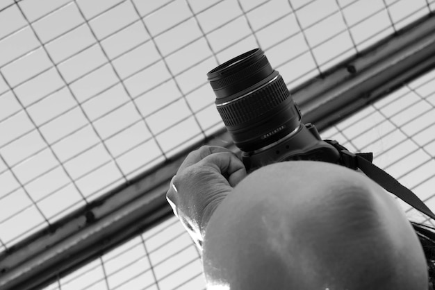 Photo close-up of cropped hand photographing with camera against fence